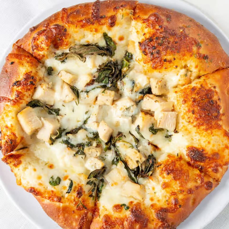 Rock Creek Pizza's chicken and spinach pizza, topped with melted mozzarella cheese and golden crust.